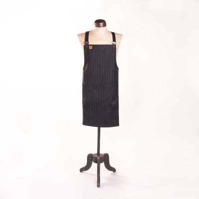 Image shows a grey pinstripe wool apron with dungaree clip fastenings, on a vintage mannequin